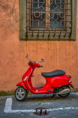 Naklejka na ściany i meble A pic of a red scooter parked under a window