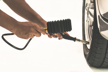 Close-up of tire pressure gauge and technician hands checking tyre pressure with master gauge before test on white background © Meng_Dakara