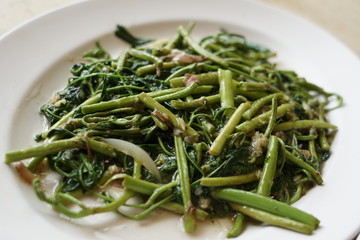 The spicy and tasty Thai stir fried water crest vegetableson the white plate.