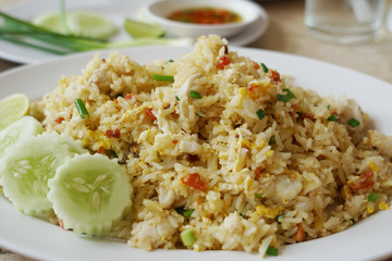 The delicious Asian crab meat fried rice with the cucumber garnish on the white plate.