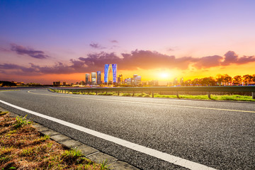 Asphalt road and Suzhou city skyline with beautiful colorful clouds at sunset.