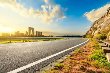 Empty asphalt road and Suzhou city skyline with beautiful clouds at sunset.