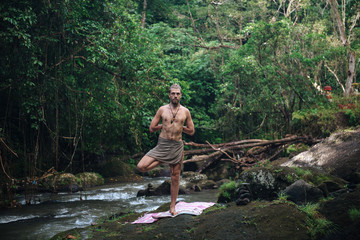 Yoga practice and meditation in nature. Man practicing near river