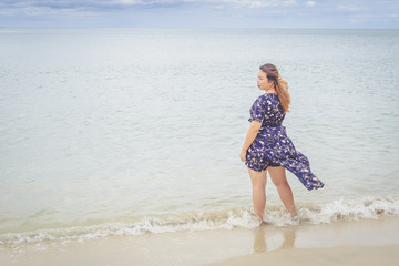 Beautiful woman in blue dress standing on the beach.