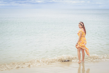 Fototapeta na wymiar Beautiful woman in yellow dress standing on the beach.