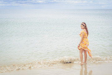 Fototapeta premium Beautiful woman in yellow dress standing on the beach.