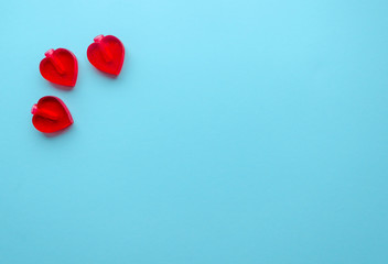 Valentine's flat lay with three small crushed red love hearts  on colorful blue background, greeting card copy space top view. Valentine's day celebration