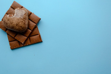 Valentine's flat lay with love chocolate gingerbread heart on colorful blue background, greeting card copy space top view. The celebration of Valentine's Day.