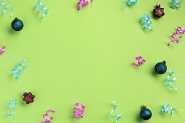 Fototapeta na wymiar Christmas, New Year, winter concept. Colorful serpentine and balls, on green background. Flat lay, top view, copy space.