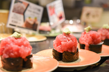 Fresh sushi on conveyor belt with blured background in sushi restaurant in Kyoto, Japan