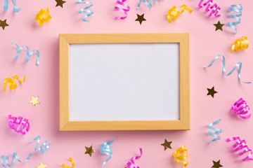 Photo frame, holiday concept. Colorful serpentine and golden stars, on pink  background. Flat lay, top view, copy space.