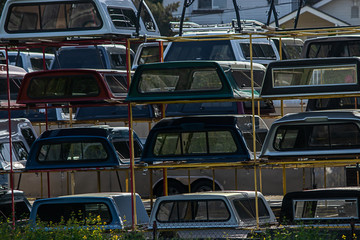 stacks of colorful campershells for trucks in a row for sale
