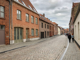Fototapeta na wymiar People Walking Along a Cobblestone Street in Bruges