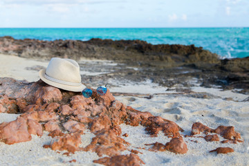 A man's straw hat hangs on a branch against the beautiful sea.Horizontally.