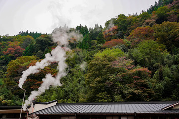 煙突からの湯煙と紅葉の山