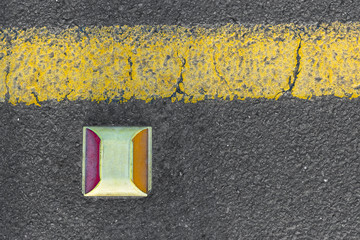 red and yellow road stud / cat eye on  black asphalt
