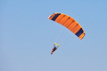 Instructor with student under canopy of a parachute in blue sky