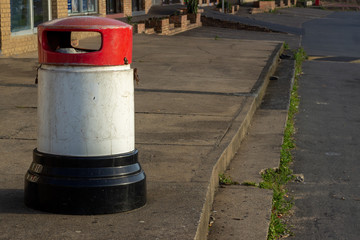 Fototapeta na wymiar red white and black trash can on concrete pavement