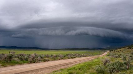 Shelf cloud storm moving over the landscape with road leading of into the distance towards the storm. © Wesley Aston
