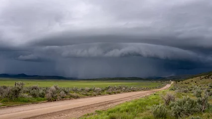 Fototapeten Shelf cloud storm moving over the landscape with road leading of into the distance towards the storm. © Wesley Aston
