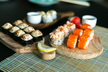sushi roll on a black background.  Asian food Sushi and soy sauce in a bowl, ginger and lemon on wooden plates. Sushi menu. Japanese food.