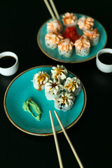 Sushi rolls in blue plate, chopsticks and soy sauce