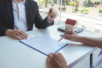 Contacting the buying or selling of real estate through a sales representative offering a contract to buy a house or apartment, condo and providing house keys for success.