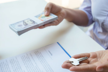 Contacting the buying or selling of real estate through a sales representative offering a contract to buy a house or apartment, condo and providing house keys for success.