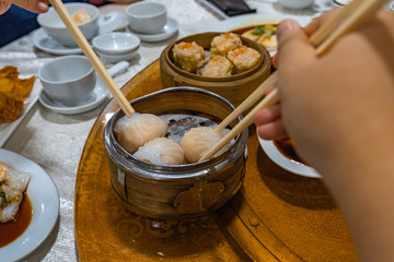 Human using chopsticks eating dimsum steamed shrimp dumpling