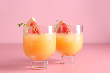 Glasses of fresh citrus juice on color background