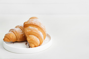 Plate with tasty croissants on white table