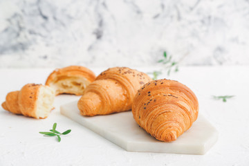 Board with tasty croissants on white background
