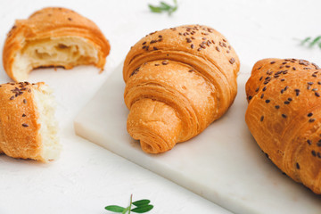 Board with tasty croissants on white background