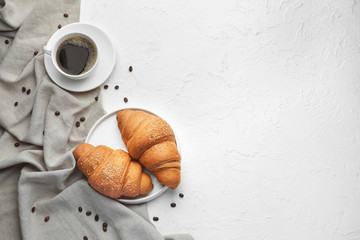 Plate with tasty croissants and cup of coffee on white background