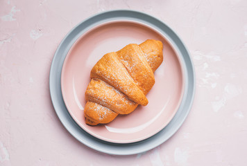 Plates with tasty croissant on color background