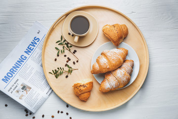Tray with tasty croissants and cup of coffee on white table