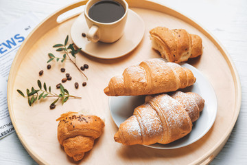 Tray with tasty croissants and cup of coffee on white table