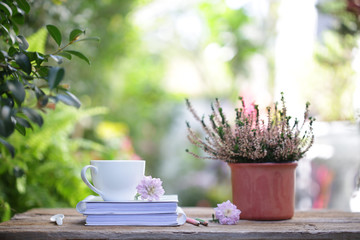 White coffee cup and pink Chrysanthemums flower with heathers plant on wooden table at outdoor