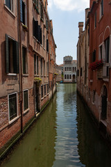 Fototapeta na wymiar Narrow Canal with Brick Buildings in Venice Italy