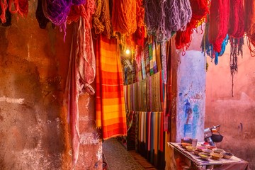 Vibrant color outside a tourist shop in Morocco, with colorful scarves, yarn and paint pigment on...