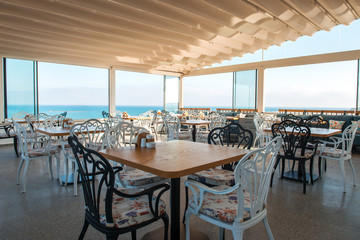 View of restaurant or cafe on beach in Gumusluk, Bodrum city of Turkey. Aegean seaside style colorful chairs, tables and flowers in Bodrum town near beautiful Aegean Sea.