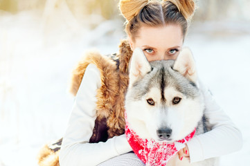 Adorable caucasian woman spending time outdoor enjoying the frosty weather with her husky pet. Photo of pretty young lady in winter outfit, piercing look of a girl and a dog
