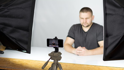 Bearded attractive male video blogger shoots video streaming for users while.