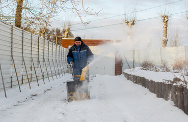 man operating snow blower to remove snow on driveway