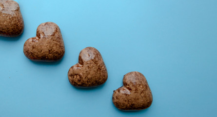 Valentine's flat lay with love chocolate gingerbread heart on colorful blue background, greeting card copy space top view. The celebration of Valentine's Day.