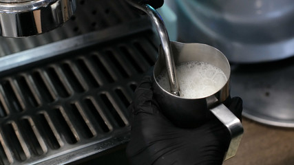 Barista at work. The process of making coffee and cacao. A glass of foaming milk. Electric Grinder Grinds Coffee Beans In Filter Holder.