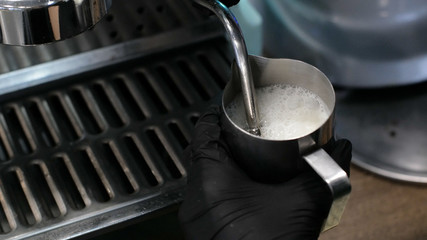 Barista at work. The process of making coffee and cacao. A glass of foaming milk. Electric Grinder Grinds Coffee Beans In Filter Holder.