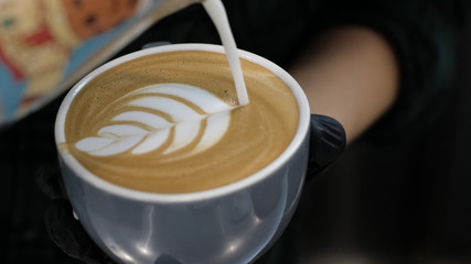 Barista at work. The process of making coffee and cacao. A glass of foaming milk. Electric Grinder Grinds Coffee Beans In Filter Holder.