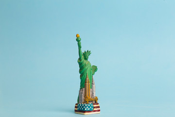 Statue of Liberty on a blue clean background. Toy model of the Statue of Liberty as a souvenir from a trip to the USA