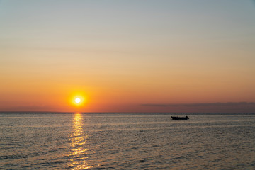 Fototapeta na wymiar Boat in the middle of the sea during sunset
